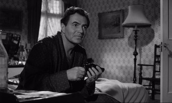 Movie still from “Lolita” (1962), directed by Stanley Kubrick – A black and white photo of a man holding a camera; Medium shot, High angle