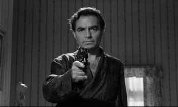 Movie still from “Lolita” (1962), directed by Stanley Kubrick – A black and white photo of a man holding a gun; Medium shot, Low angle