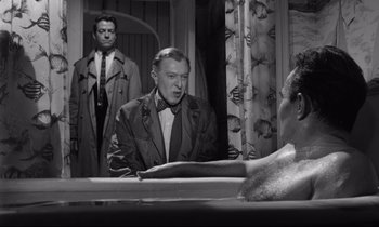 Movie still from “Lolita” (1962), directed by Stanley Kubrick – A man is sitting at a table in a room; Medium shot, Over the shoulder angle