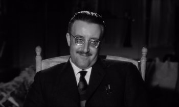 Movie still from “Lolita” (1962), directed by Stanley Kubrick – An older man wearing a suit and tie sitting in a chair; Close Up shot, Low angle