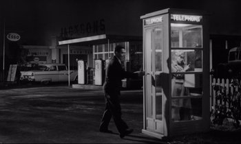 Movie still from “Lolita” (1962), directed by Stanley Kubrick – A black and white photo of a man walking past a phone booth; Wide shot, Low angle