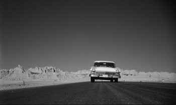 Movie still from “Lolita” (1962), directed by Stanley Kubrick – An old car driving down a road in the middle of the desert; Extreme Wide shot, Low angle