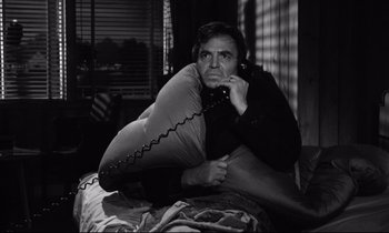 Movie still from “Lolita” (1962), directed by Stanley Kubrick – A man sitting on a bed talking on the phone; Medium shot, High angle