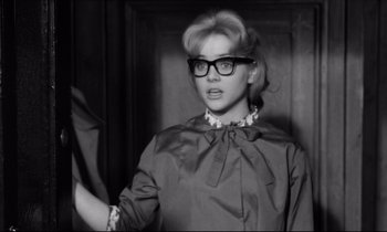 Movie still from “Lolita” (1962), directed by Stanley Kubrick – A black and white photo of a woman wearing glasses; Close Up shot, Over the shoulder angle