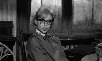 Movie still from “Lolita” (1962), directed by Stanley Kubrick – A woman sitting in a chair wearing glasses; Medium shot, Over the shoulder angle