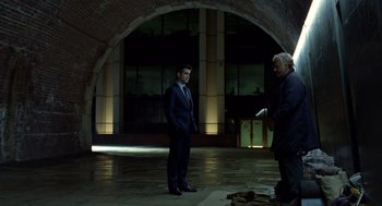 Movie still from “London Boulevard” (2010), directed by William Monahan – A man in a business suit standing next to another man in a business suit; Wide shot, Over the shoulder angle
