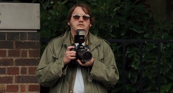Movie still from “London Boulevard” (2010), directed by William Monahan – A man taking a picture with a camera; Close Up shot, Over the shoulder angle