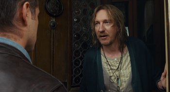 Movie still from “London Boulevard” (2010), directed by William Monahan – A man with long hair standing in front of a wall; Close Up shot, Over the shoulder angle