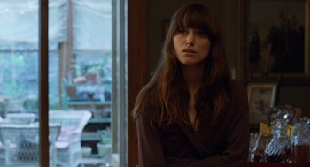 Movie still from “London Boulevard” (2010), directed by William Monahan – A beautiful woman with long hair sitting in front of a window; Close Up shot, Over the shoulder angle