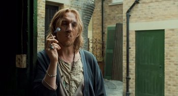 Movie still from “London Boulevard” (2010), directed by William Monahan – A man holding a cell phone up to his ear; Medium shot, Over the shoulder angle