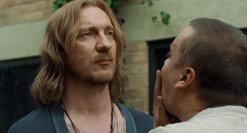 Movie still from “London Boulevard” (2010), directed by William Monahan – A man with long blonde hair is talking to another man; Close Up shot, Over the shoulder angle