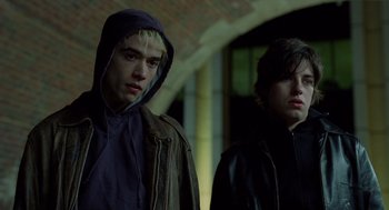 Two young men standing next to each other in a dark room