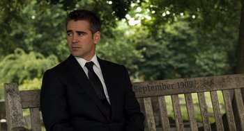 Movie still from “London Boulevard” (2010), directed by William Monahan – A man in a suit and tie sitting on a park bench; Medium shot, Over the shoulder angle