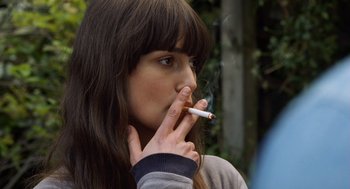 Movie still from “London Boulevard” (2010), directed by William Monahan – A young woman is smoking a cigarette outside; Close Up shot, Over the shoulder angle