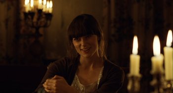 Movie still from “London Boulevard” (2010), directed by William Monahan – A woman sitting in front of a lit candle in a dark room; Close Up shot, Over the shoulder angle