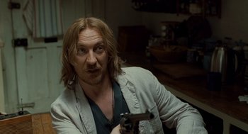 Movie still from “London Boulevard” (2010), directed by William Monahan – A man holding a gun in a room; Close Up shot, Over the shoulder angle