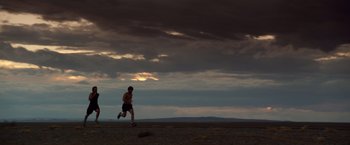 Movie still from “Lone Survivor” (2013), directed by Peter Berg – A man is running on a dirt field; Extreme Wide shot, Low angle