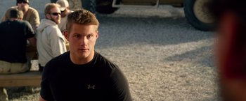Movie still from “Lone Survivor” (2013), directed by Peter Berg – A man in a black shirt is standing in a parking lot; Close Up shot, Over the shoulder angle