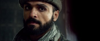 Movie still from “Lone Survivor” (2013), directed by Peter Berg – A man with a beard wearing a hat and a scarf; Close Up shot, Over the shoulder angle