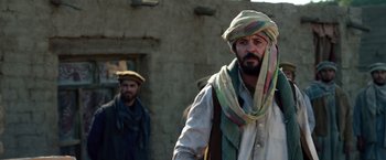 Movie still from “Lone Survivor” (2013), directed by Peter Berg – A man with a beard wearing a turban and a scarf; Medium shot, Over the shoulder angle