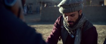 Movie still from “Lone Survivor” (2013), directed by Peter Berg – A man with a beard wearing a hat and a scarf; Close Up shot, Over the shoulder angle
