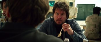 Movie still from “Lone Survivor” (2013), directed by Peter Berg – A man sitting at a table eating food; Close Up shot, Over the shoulder angle