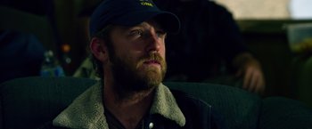 Movie still from “Lone Survivor” (2013), directed by Peter Berg – A man with a beard wearing a hat and jacket; Close Up shot, Over the shoulder angle