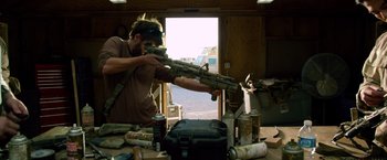 Movie still from “Lone Survivor” (2013), directed by Peter Berg – A man is holding a gun in a room; Medium shot, Over the shoulder angle
