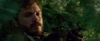 Movie still from “Lone Survivor” (2013), directed by Peter Berg – A person with a beard near a tree; Close Up shot, Over the shoulder angle