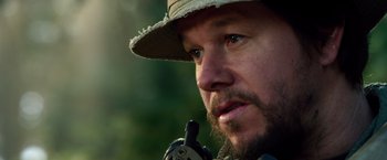 Movie still from “Lone Survivor” (2013), directed by Peter Berg – A person wearing a hat and holding a rifle; Close Up shot, Over the shoulder angle
