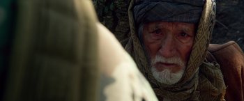 Movie still from “Lone Survivor” (2013), directed by Peter Berg – An old man with a beard wearing a head covering; Close Up shot, Over the shoulder angle