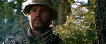Movie still from “Lone Survivor” (2013), directed by Peter Berg – A person wearing a hat near a tree; Close Up shot, Over the shoulder angle