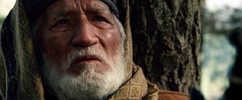 Movie still from “Lone Survivor” (2013), directed by Peter Berg – An old man with a white beard wearing a blanket; Close Up shot, Low angle