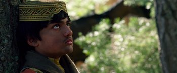 Movie still from “Lone Survivor” (2013), directed by Peter Berg – A young man wearing an oriental hat looks upward; Close Up shot, Low angle
