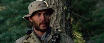 Movie still from “Lone Survivor” (2013), directed by Peter Berg – A man wearing a hat and a camouflage uniform; Close Up shot, Over the shoulder angle