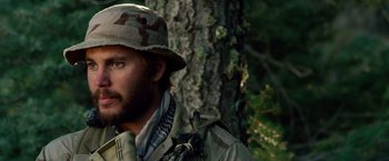 Movie still from “Lone Survivor” (2013), directed by Peter Berg – A person wearing a hat near a tree; Close Up shot, Over the shoulder angle