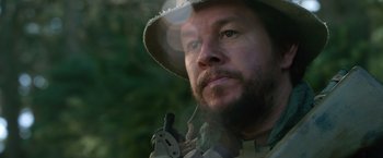 Movie still from “Lone Survivor” (2013), directed by Peter Berg – A person wearing a hat and holding a gun; Close Up shot, Low angle