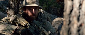 Movie still from “Lone Survivor” (2013), directed by Peter Berg – A man with a beard wearing a hat and holding a rifle; Close Up shot, Over the shoulder angle