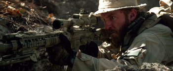 Movie still from “Lone Survivor” (2013), directed by Peter Berg – A man with a beard is holding a rifle; Close Up shot, Over the shoulder angle