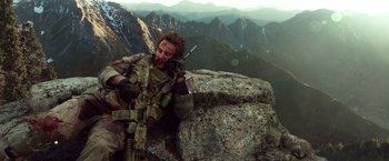 Movie still from “Lone Survivor” (2013), directed by Peter Berg – A person with a gun on top of a mountain; Medium shot, Low angle