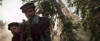 Movie still from “Lone Survivor” (2013), directed by Peter Berg – A man with a beard is standing in the woods; Medium shot, Low angle