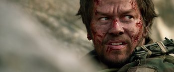 Movie still from “Lone Survivor” (2013), directed by Peter Berg – A man's face covered in blood; Close Up shot, Low angle