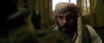 Movie still from “Lone Survivor” (2013), directed by Peter Berg – A bearded man wearing a turban looking into the camera; Close Up shot, Over the shoulder angle