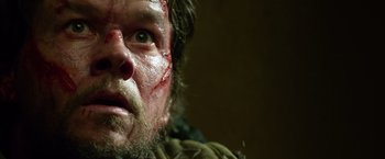 Movie still from “Lone Survivor” (2013), directed by Peter Berg – A man's face with blood on his face; Close Up shot, Low angle
