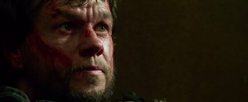 Movie still from “Lone Survivor” (2013), directed by Peter Berg – A person with a bloody face; Close Up shot, Low angle