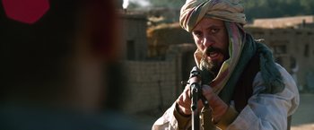 Movie still from “Lone Survivor” (2013), directed by Peter Berg – A man with a beard is holding a rifle; Close Up shot, Over the shoulder angle