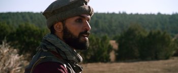 Movie still from “Lone Survivor” (2013), directed by Peter Berg – A man with a beard wearing a hat and a scarf; Close Up shot, Over the shoulder angle