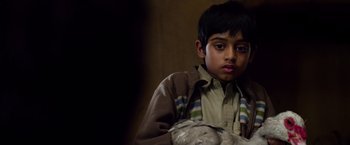 Movie still from “Lone Survivor” (2013), directed by Peter Berg – A young boy is holding a stuffed animal in his hands; Close Up shot, Over the shoulder angle