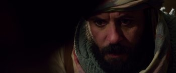 Movie still from “Lone Survivor” (2013), directed by Peter Berg – A man with a beard wearing a hat and a scarf; Close Up shot, Over the shoulder angle