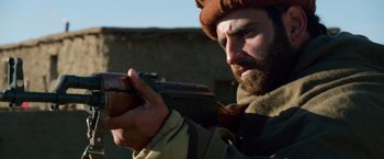 Movie still from “Lone Survivor” (2013), directed by Peter Berg – A man with a beard holding a rifle; Close Up shot, Low angle